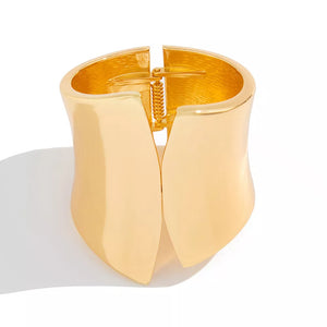 Sculptural gold-toned cuff bracelet with a spring hinge closure.