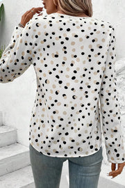 White polka dot blouse with long sleeves and a button-down front.
