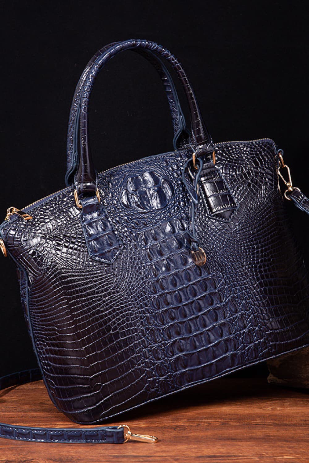 Dark blue crocodile embossed satchel with shoulder strap and gold hardware.