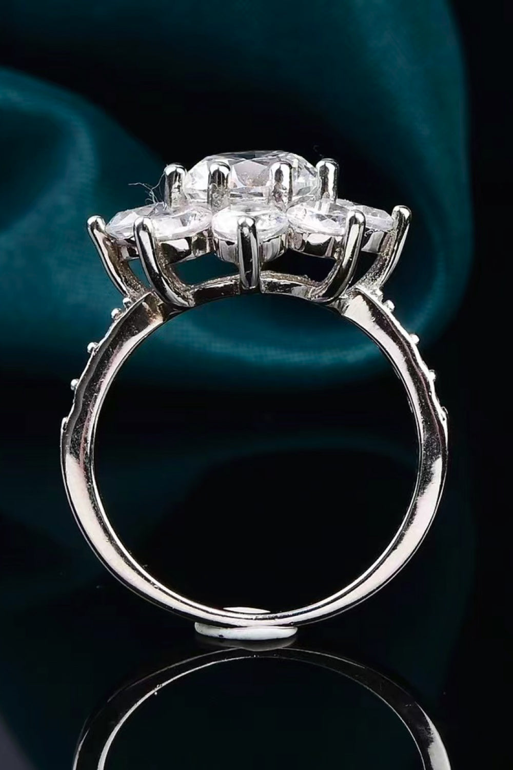 Silver moissanite engagement ring with a central stone and petal-shaped accents.