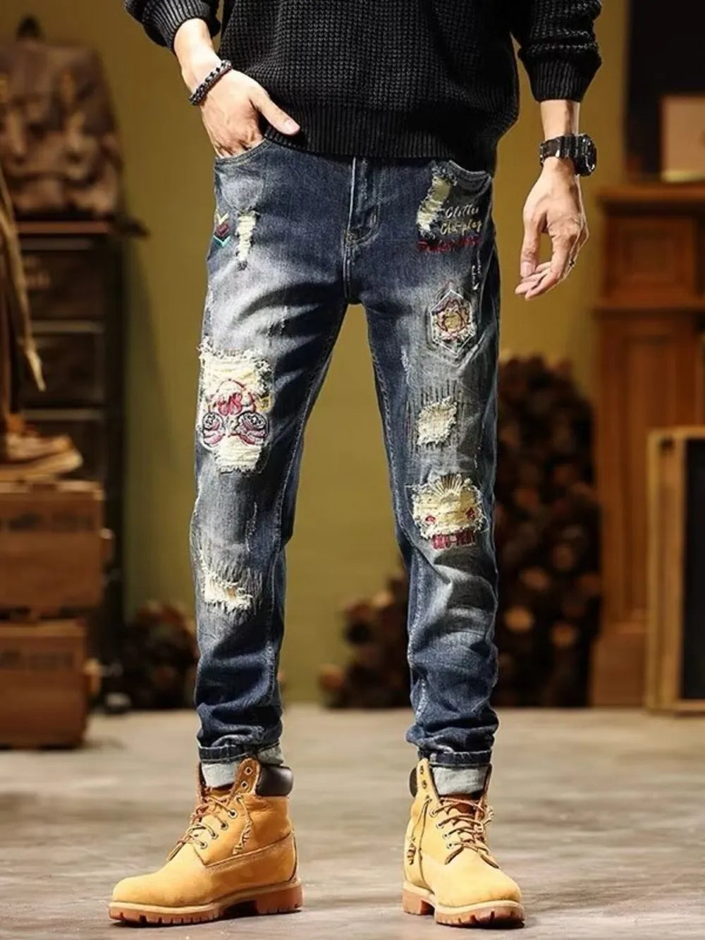 Blue distressed slim fit jeans with embroidered patches and cuffed hems.