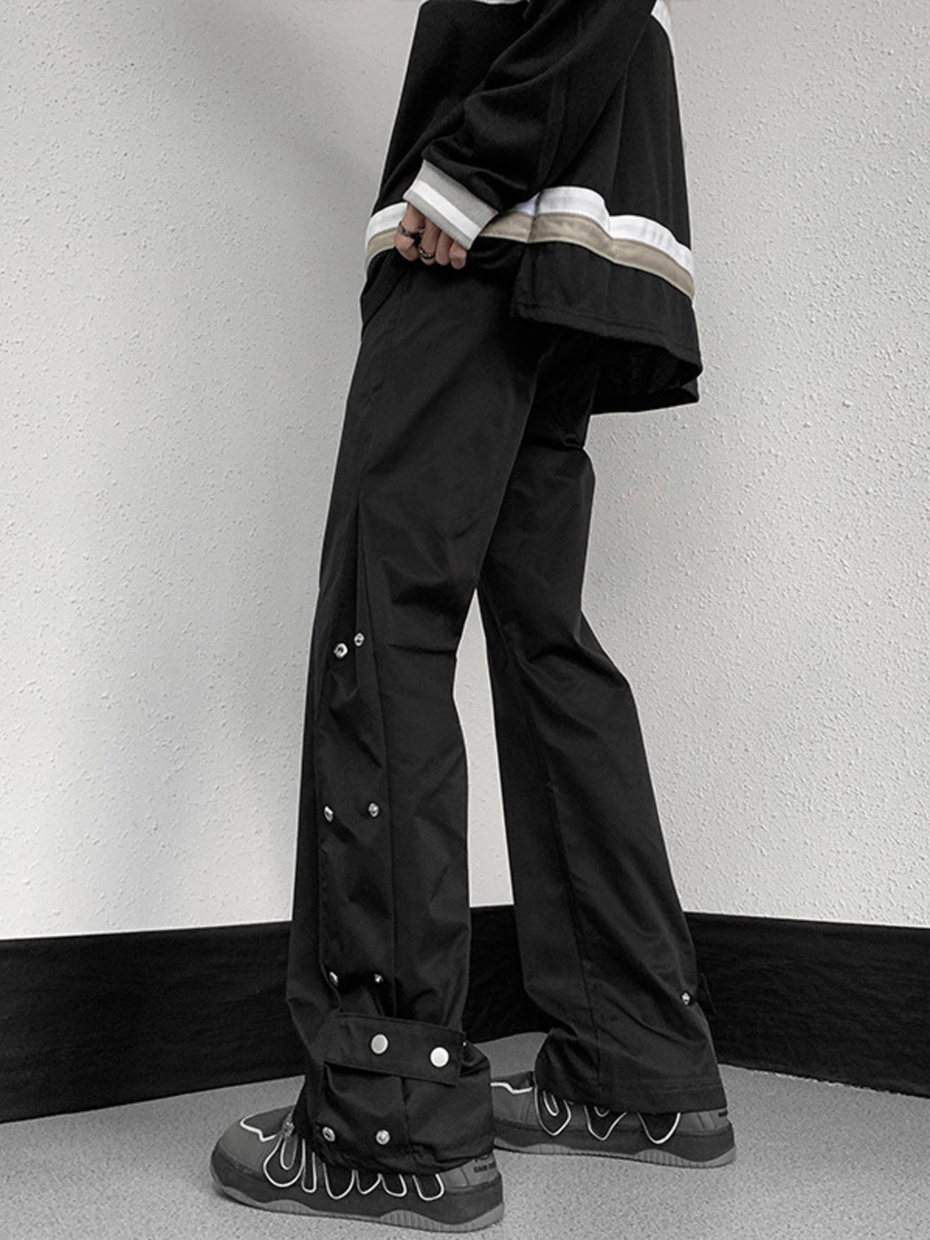 Men's black snap button loose fit sweatpants with adjustable ankle detail.