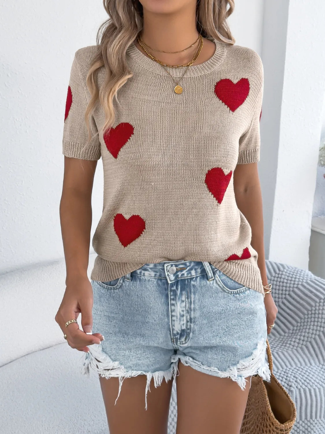 Tan knit t-shirt with red heart pattern and short sleeves.