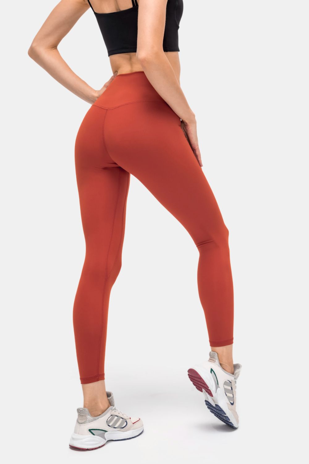 StealthFit pocketed leggings in brick red, high-waisted, full-length, with v-seam detail.