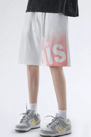Men's white casual shorts with pink gradient lettering and drawstring waist.