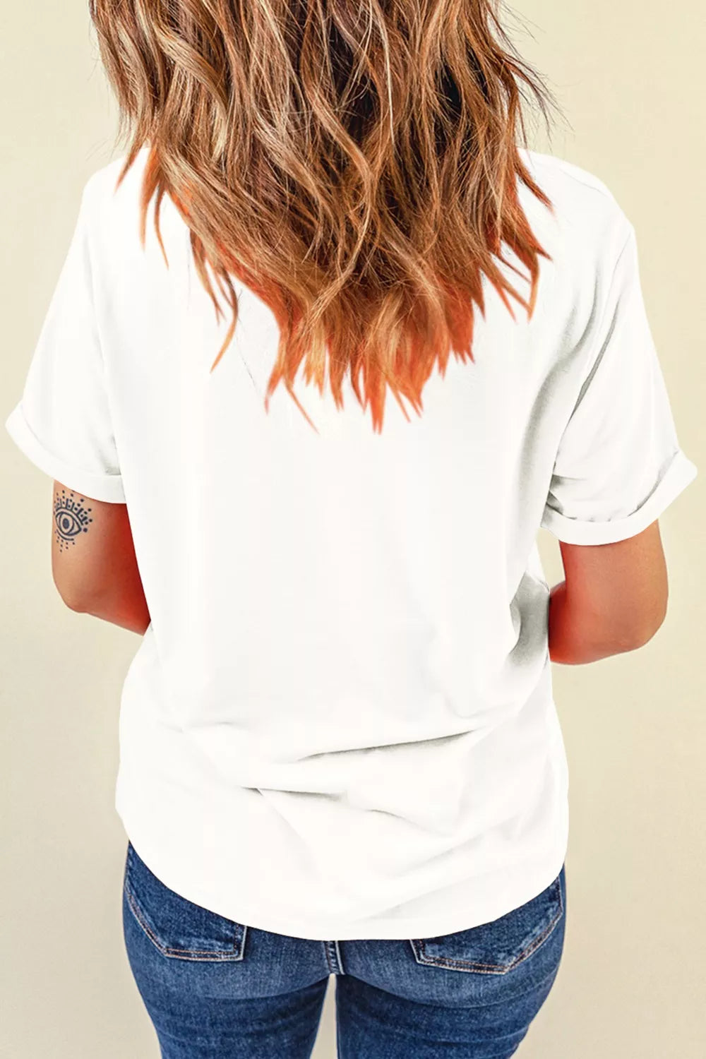 White cotton t-shirt with rolled sleeves and a subtle eye tattoo on the arm.
