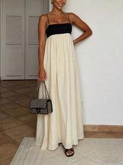 Elegant two-tone maxi dress with spaghetti straps, black bodice, cream skirt, and flowing silhouette.