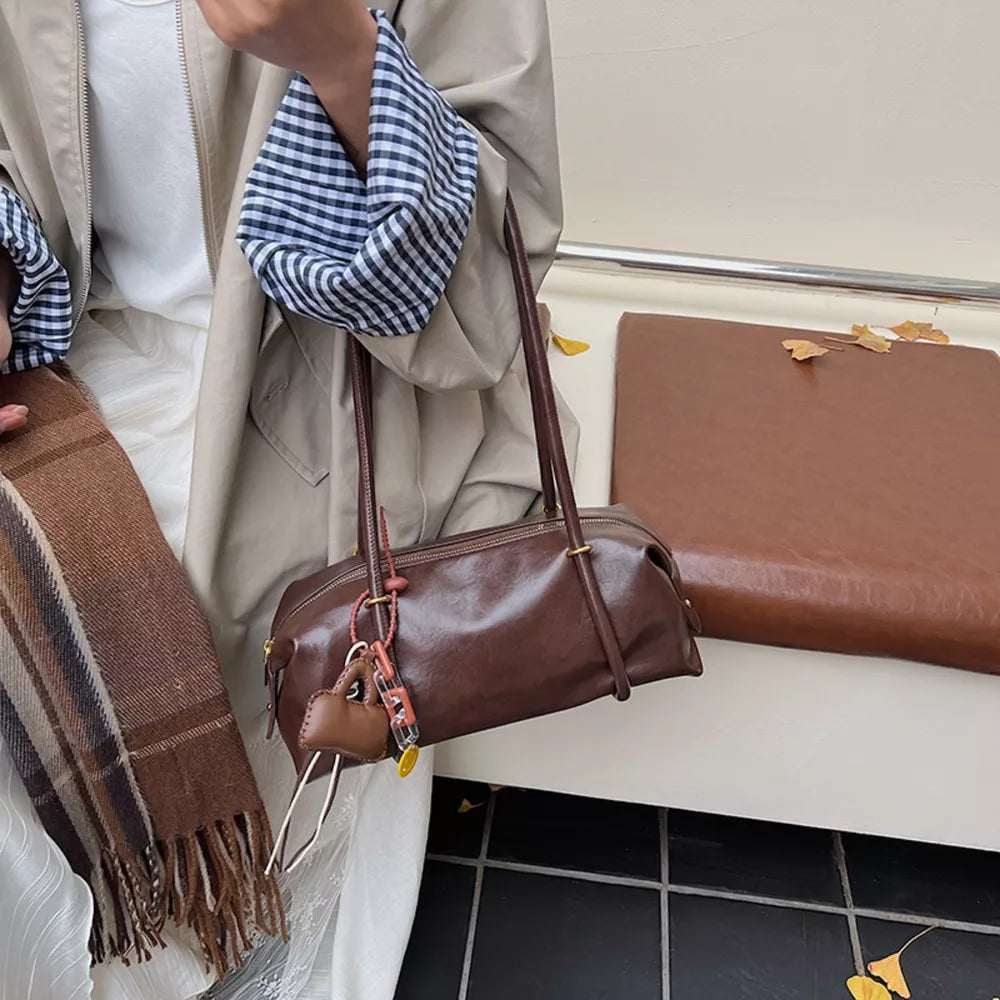 Chic brown pu leather shoulder bag with charm detail and zipper closure.