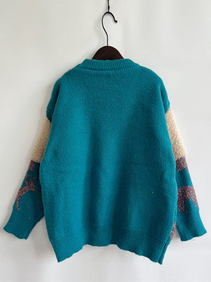 Sky blue acrylic sweater with sequin-trimmed Christmas tree pattern on sleeves and tan accents.