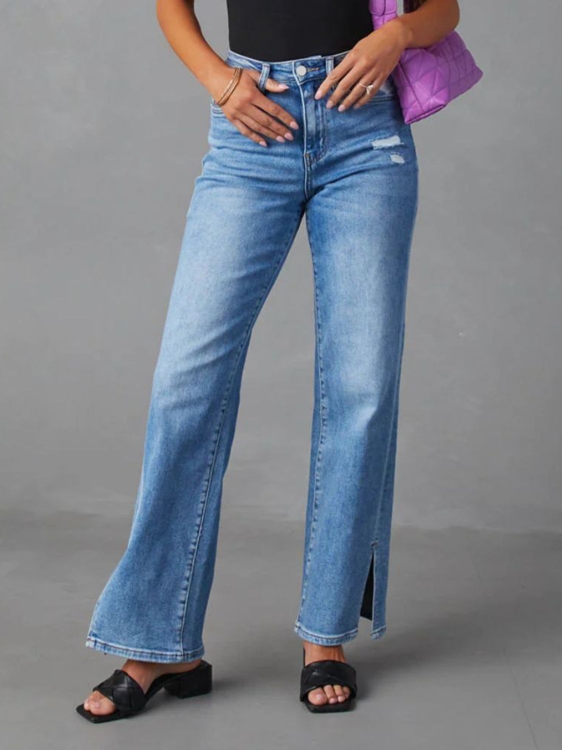 Medium wash cotton blend flare jeans with split hem detail and distressed accents.