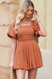 Ochre square neck puff sleeve romper with cinched waist and pleated skirt.
