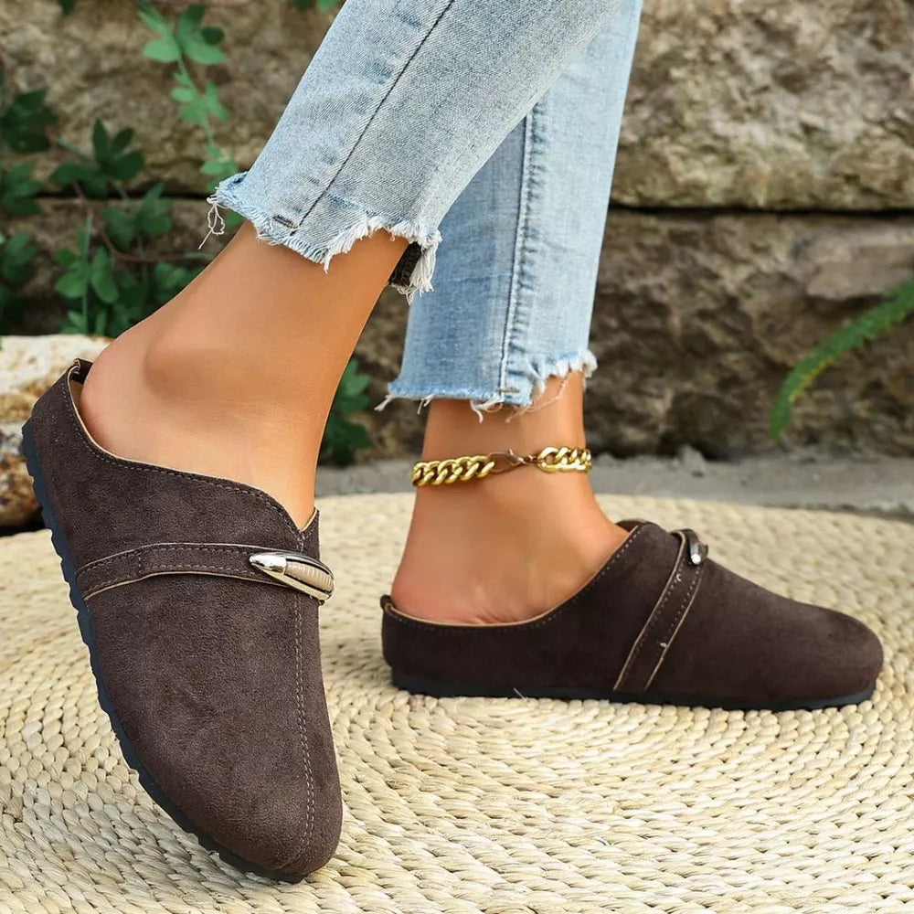 Brown slip-on flats with round toe and decorative buckle detail.