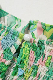 Green floral smocked yoke blouse with voluminous sleeves and a pearl button detail.