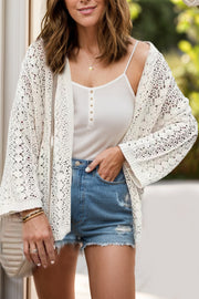 Open-knit crochet cardigan in white with bell sleeves, styled with a cami and denim shorts.