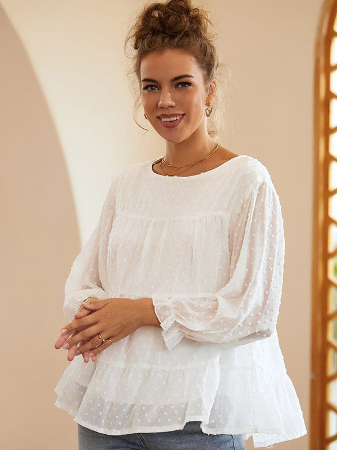White tiered Swiss dot peasant blouse with long sleeves and ruffled cuffs.