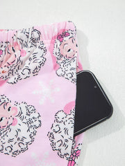 Pink pajama pants with Santa print and snowflake pattern, featuring a side pocket holding a smartphone.