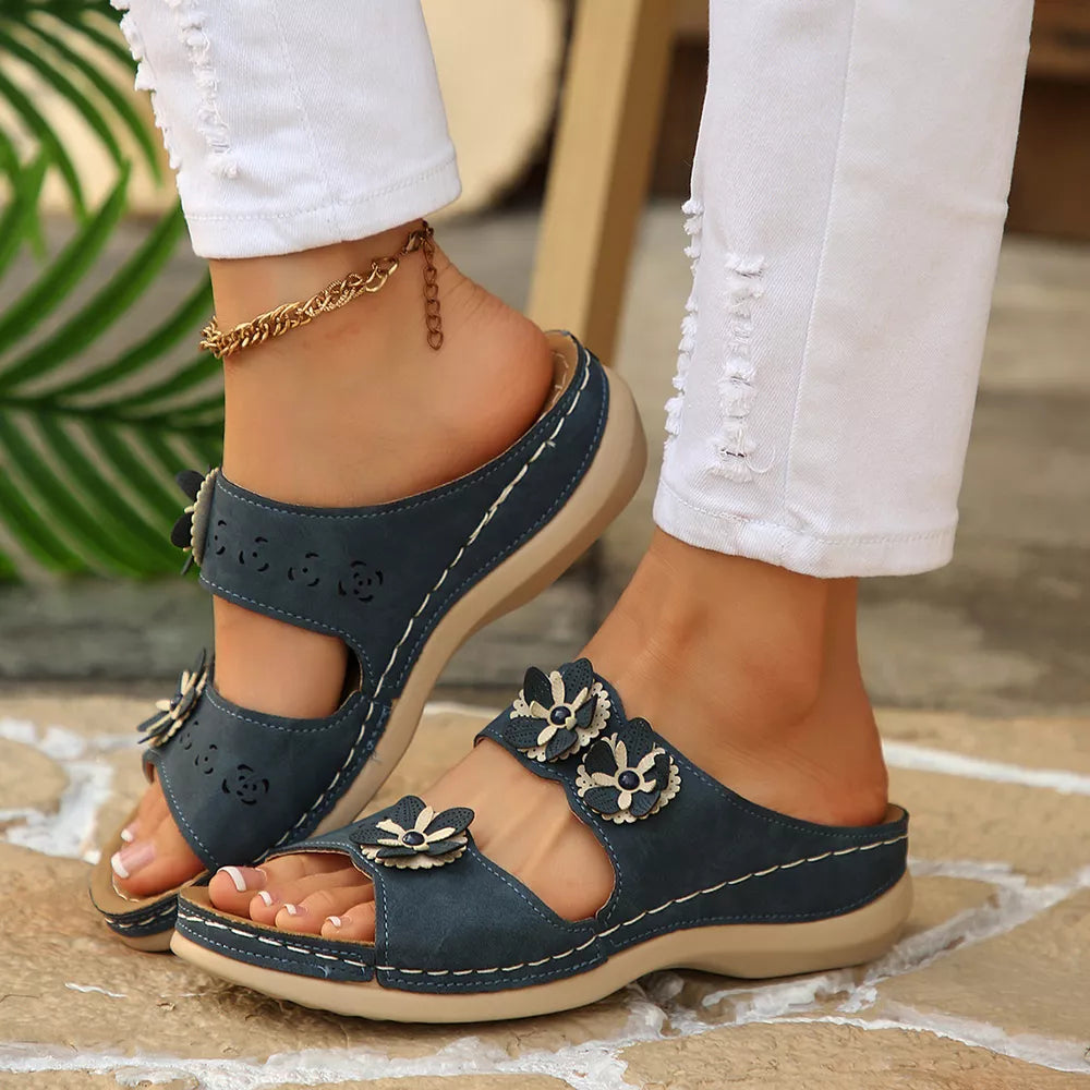 Navy blue sandals with floral appliqués and cut-out details.