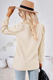 Ivory diamond-textured puff sleeve blouse with a round neckline.