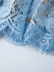Blue lace dress detail with fringed hem and intricate floral pattern.