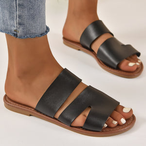 Black open toe flat sandals with two wide straps and a cut-out detail.