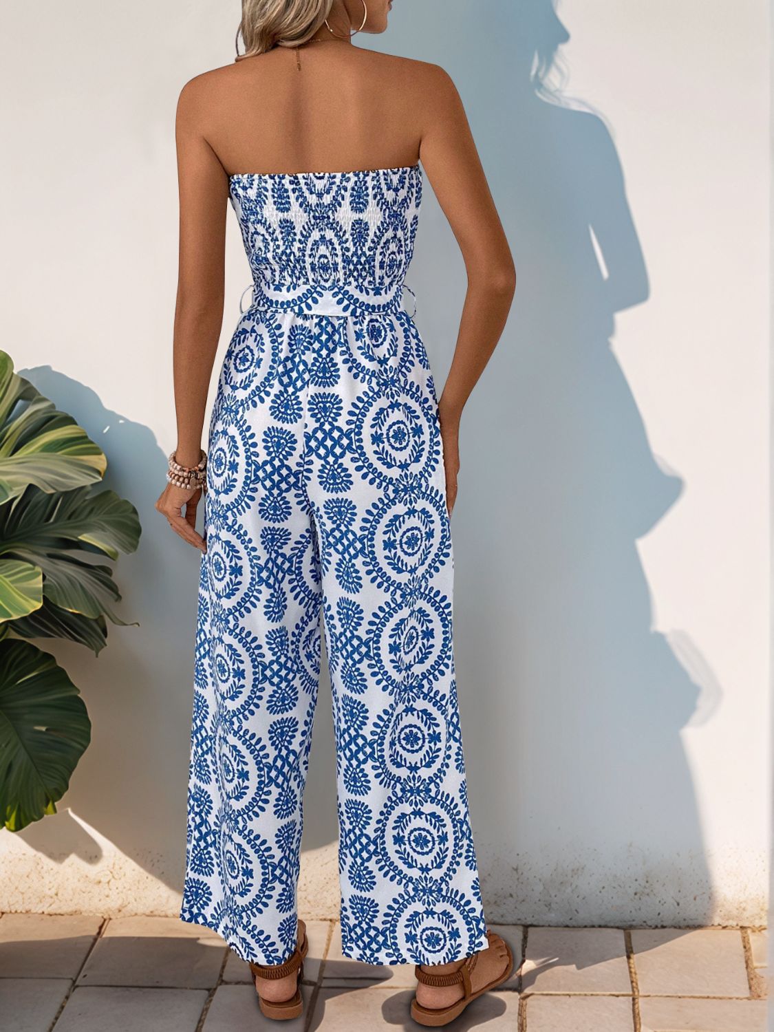 Blue bustier jumpsuit with wide legs and a decorative button belt.