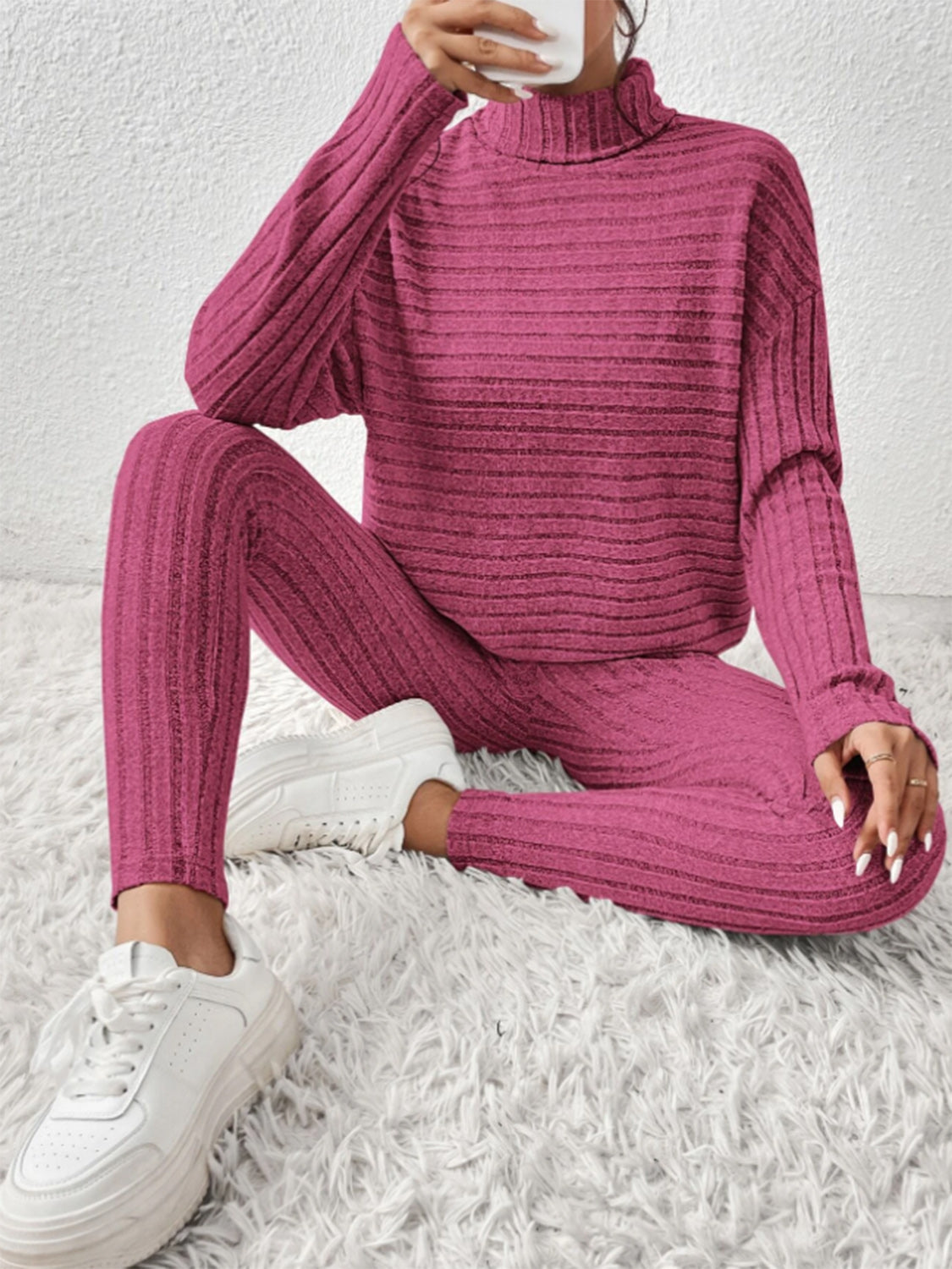 Textured turtleneck lounge set in hot pink with ribbed detail, styled with white sneakers.