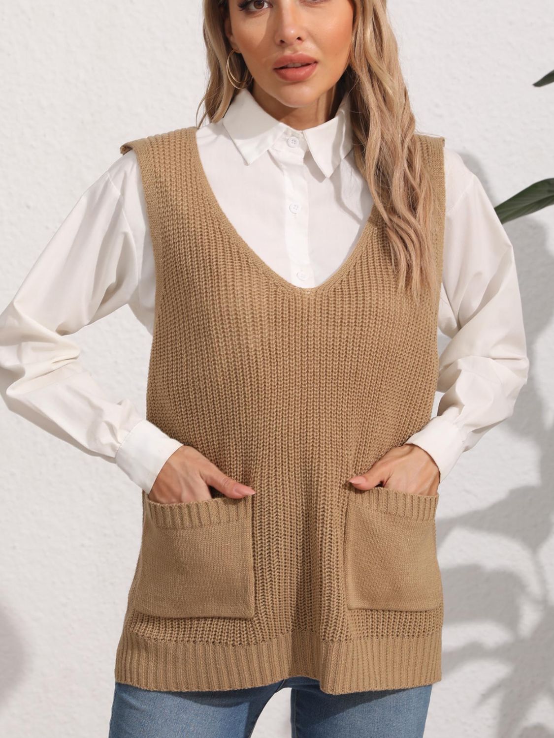 Camel oversized knit vest with V-neck and patch pockets, styled over a white shirt.