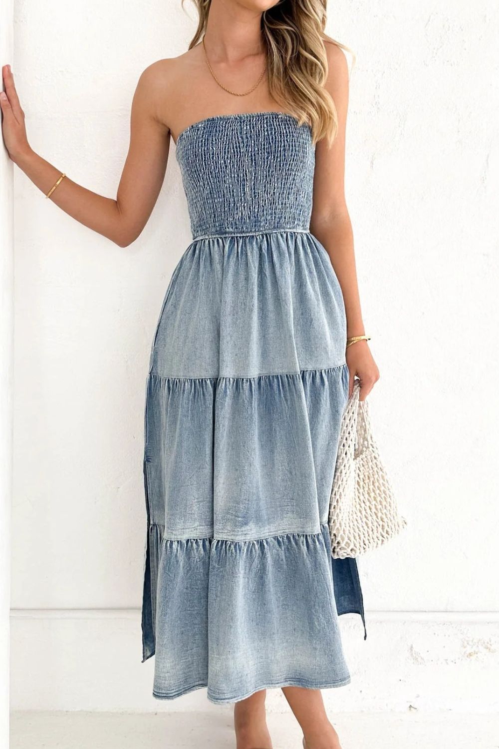 Light blue smocked denim strapless maxi dress with tiered skirt and side slits.