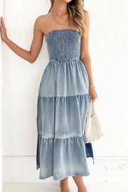 Light blue smocked denim strapless maxi dress with tiered skirt and side slits.