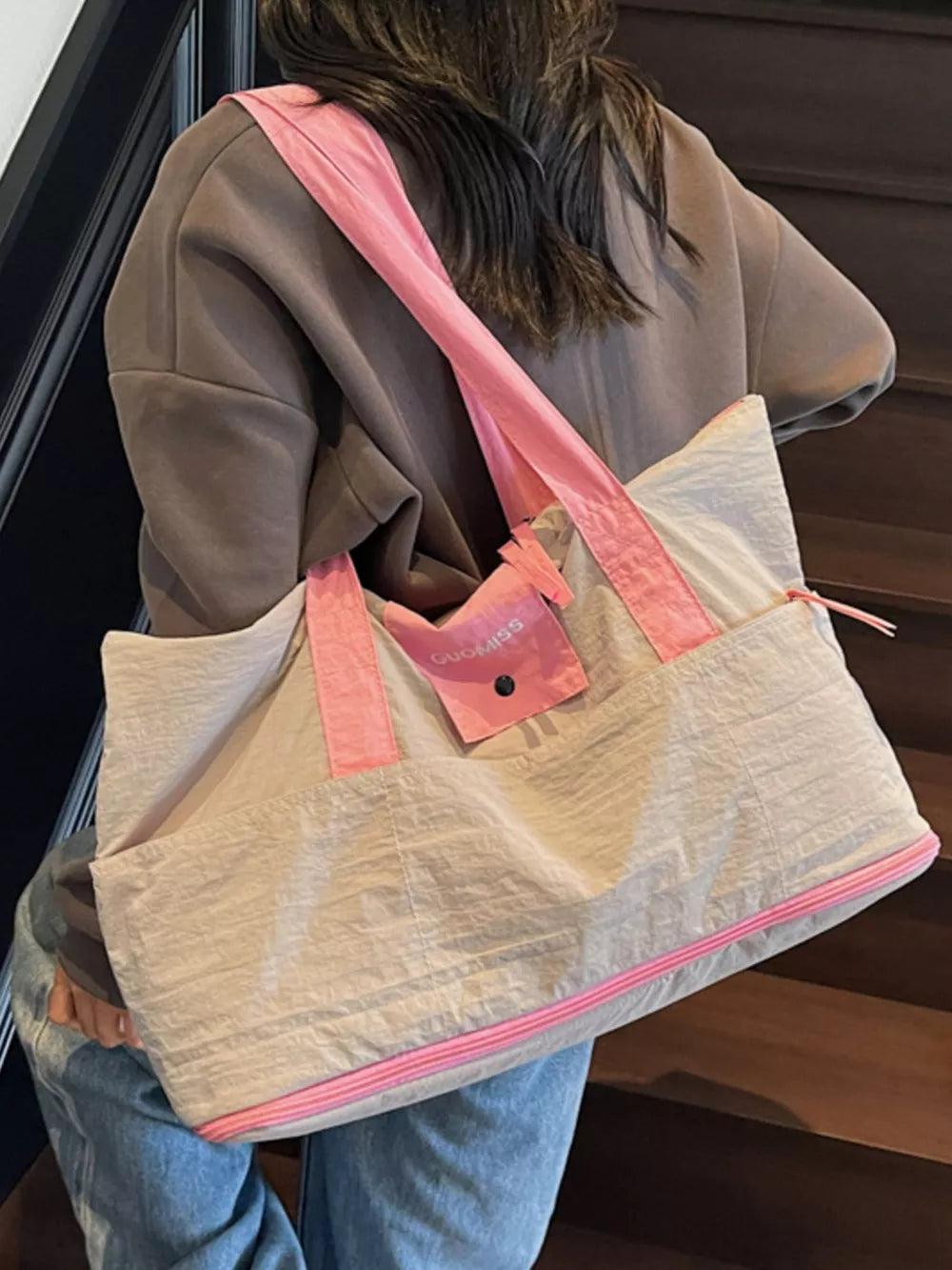 Premium two-tone nylon travel bag in beige with pink accents, featuring a pink strap and zipper detail.