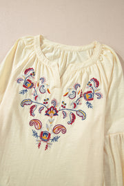 Pastel yellow embroidered blouse with V-neck and poet sleeves.