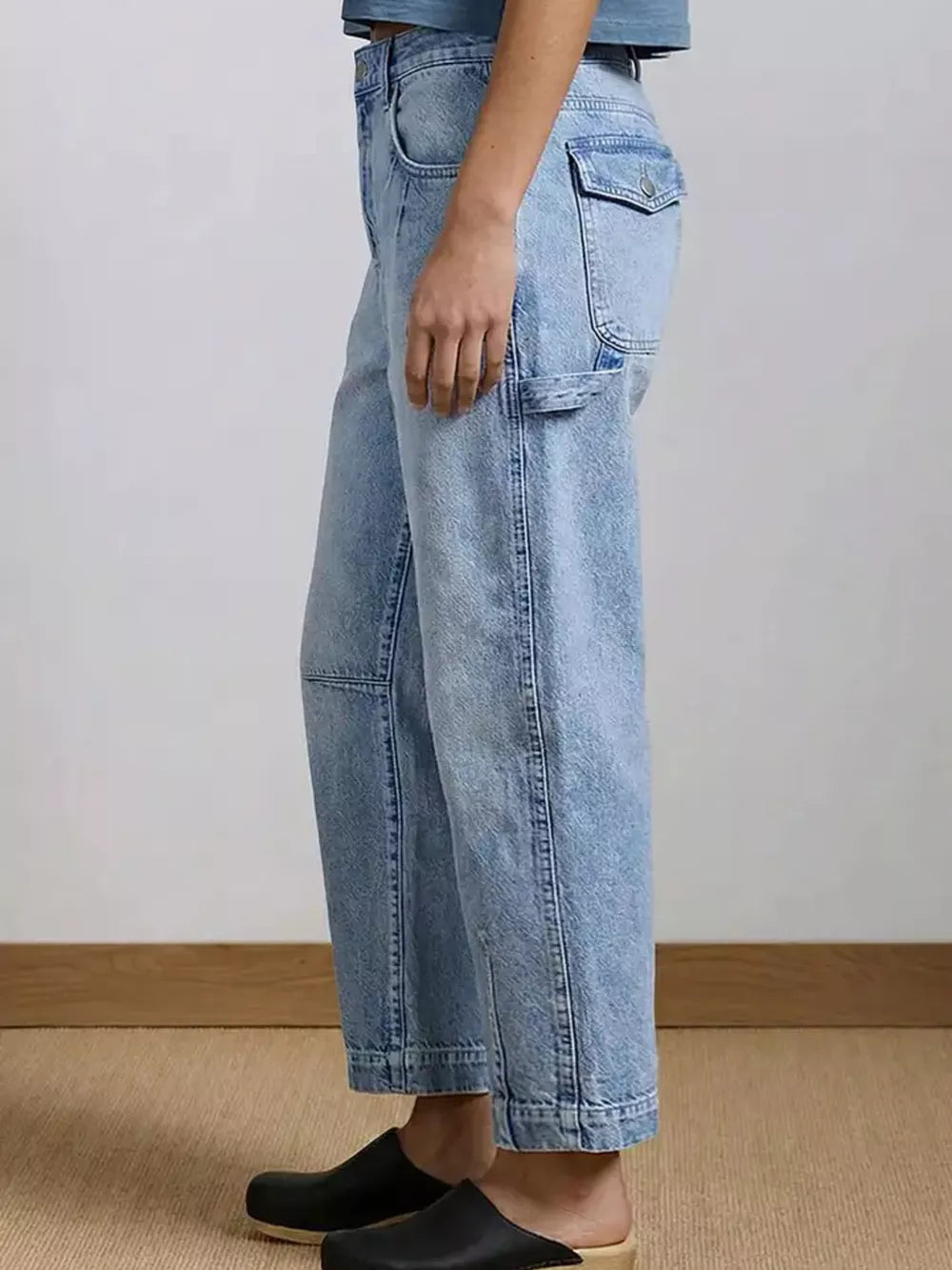 Light wash denim maternity jeans with wide legs and buttoned flap pocket detail.