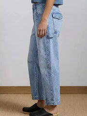 Light wash denim maternity jeans with wide legs and buttoned flap pocket detail.