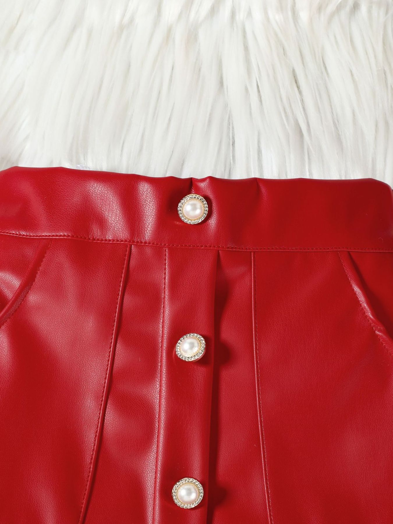 Red faux leather baby skirt with decorative pearl buttons and pleats.