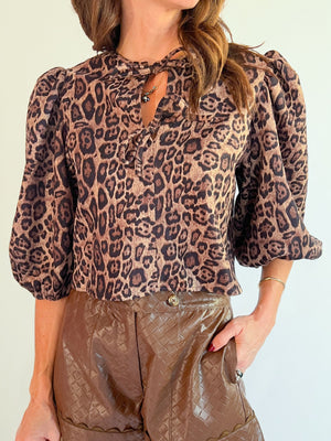Leopard print blouse with puff sleeves and a bow tie neckline.