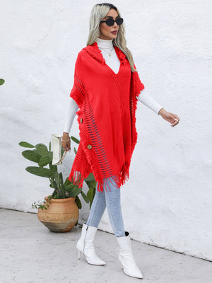 Red knit poncho with fringe, wooden buttons, and open knit detail.