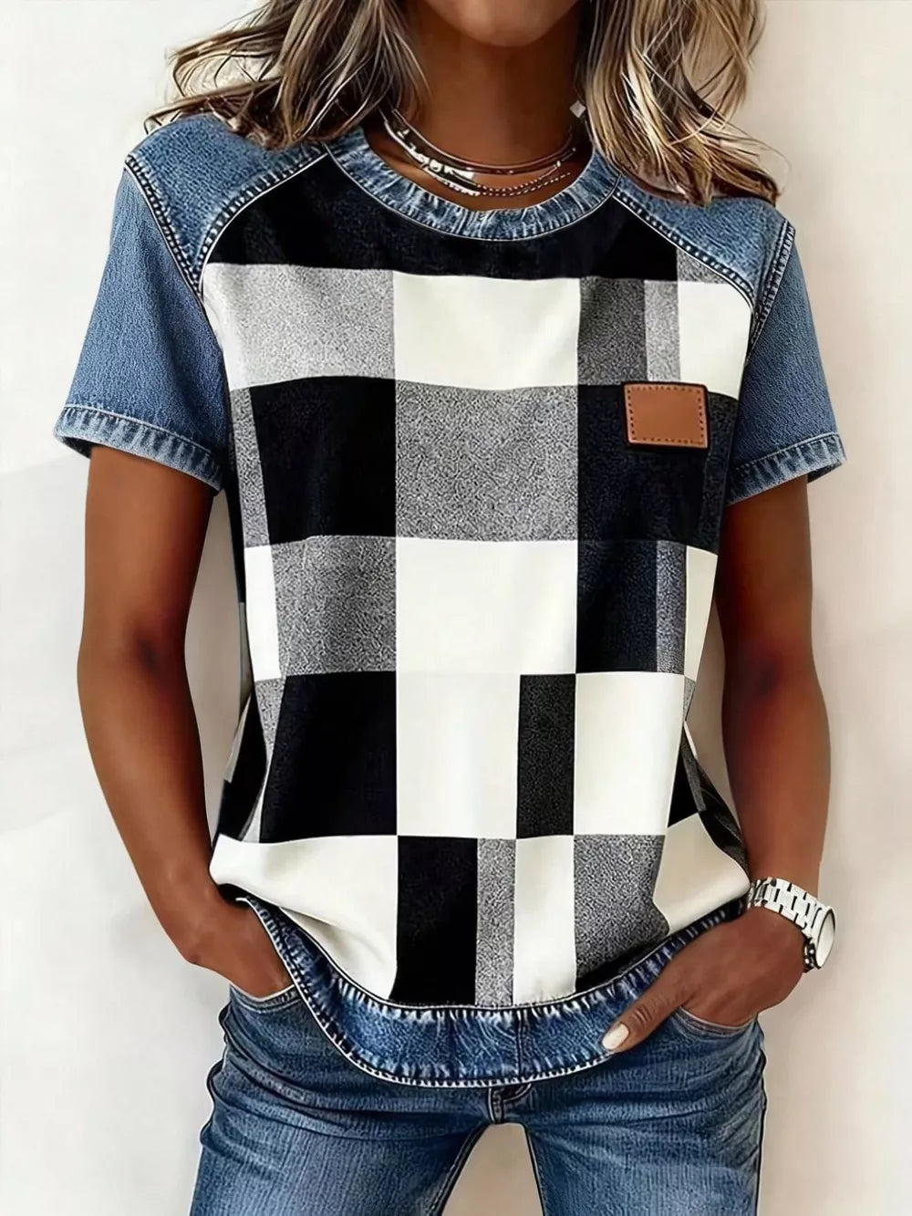 Denim patchwork shirt with black and white buffalo check front, short sleeves, and a brown leather patch detail.