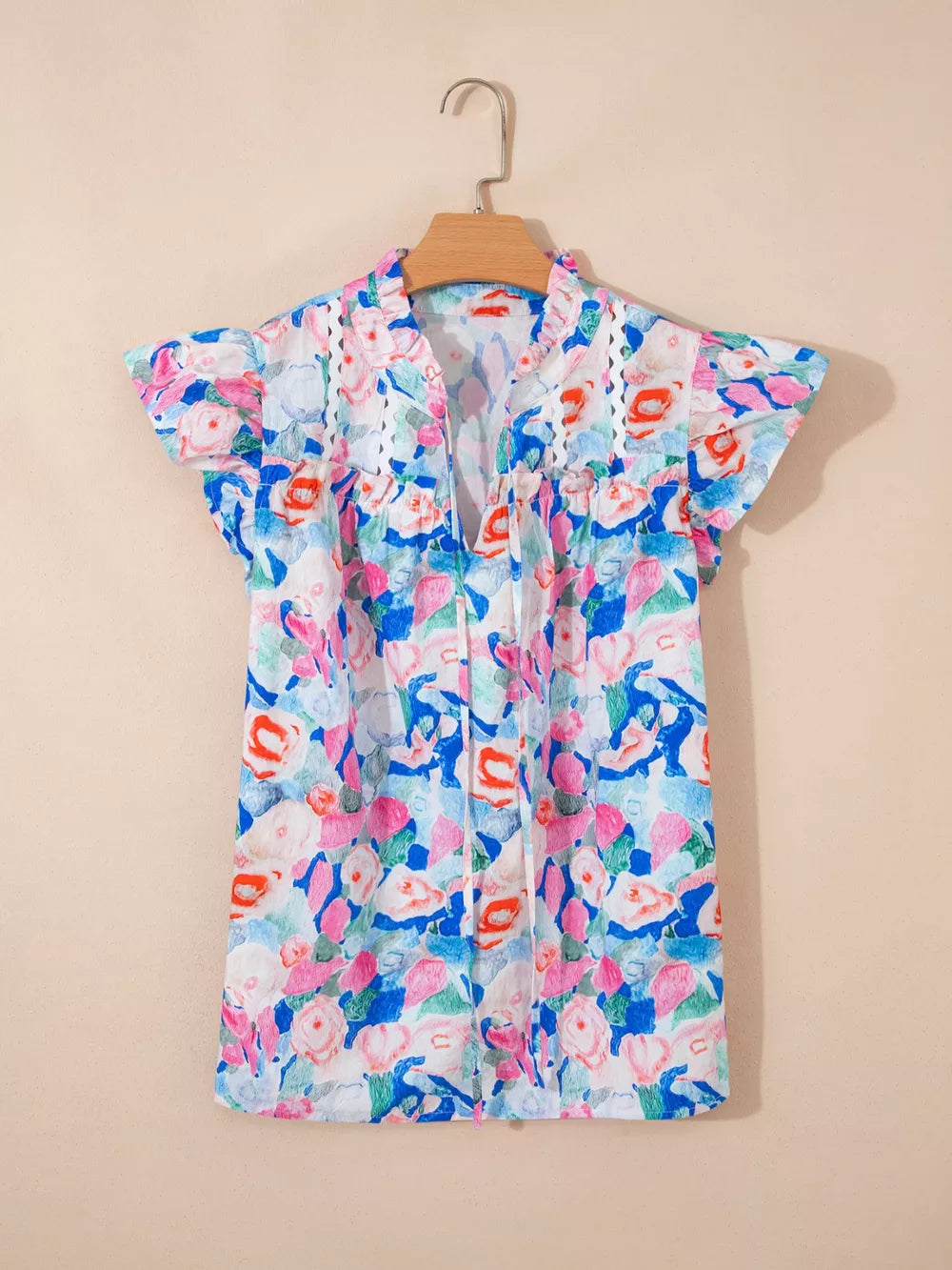 Vibrant floral tie neck cotton blouse with ruffle sleeves and eyelet trim.