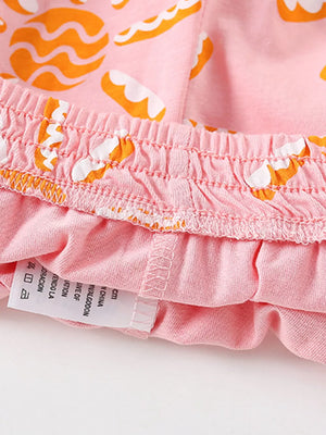 Pink cotton toddler shorts with orange and white cookie pattern and elastic waistband.