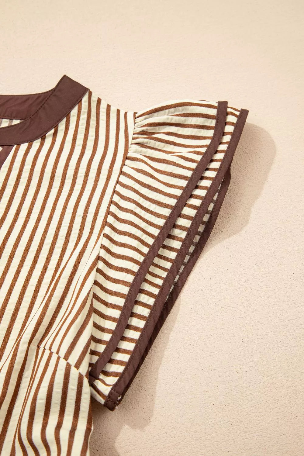 Brown and white striped midi dress with ruffled sleeves and brown trim.