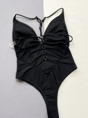 Black one-piece swimsuit with plunge neckline, backless design, and ring details.