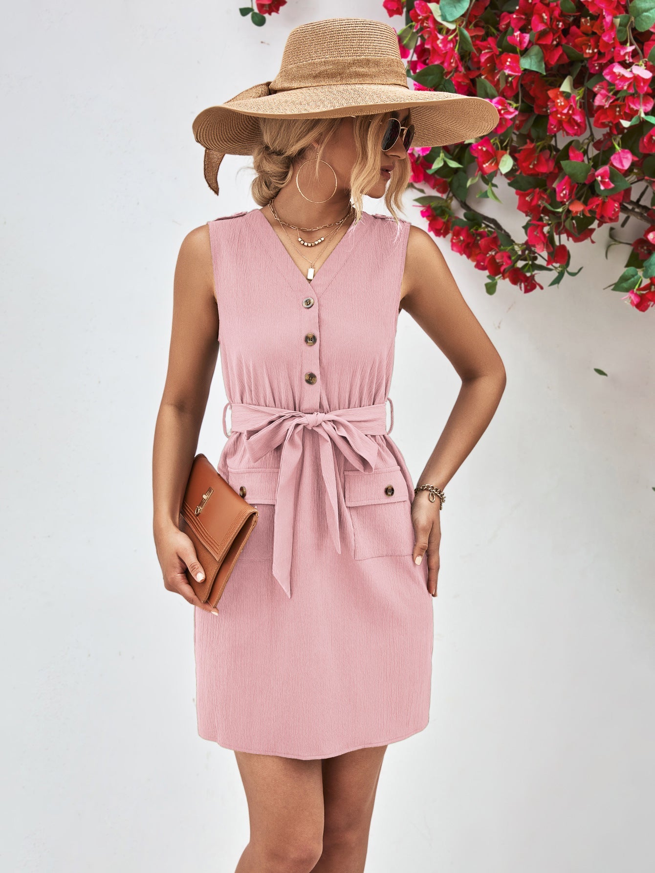 Button-down tie-waist sleeveless shirtdress in blush pink with buttoned pockets and a belted waist.