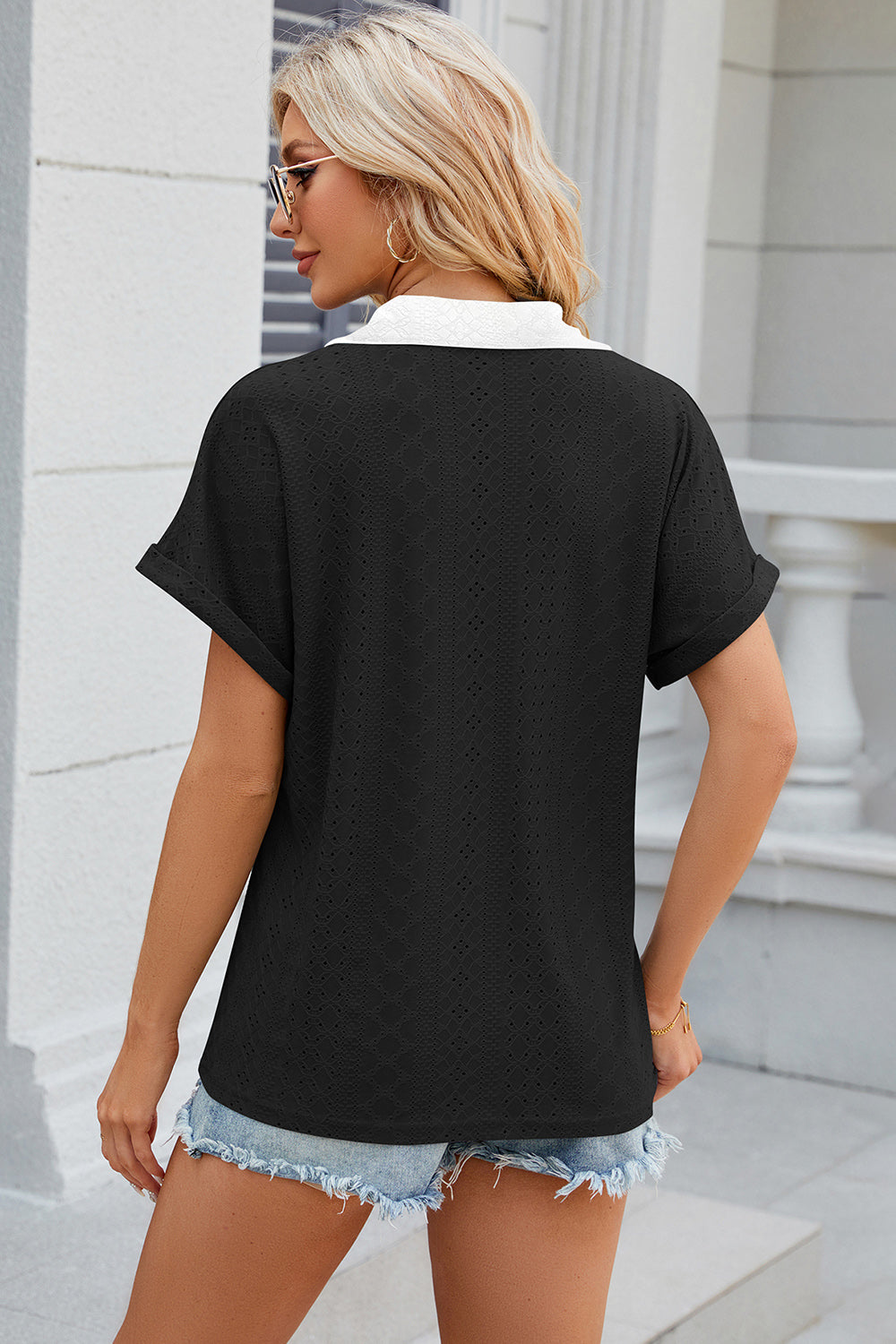 Black perforated panel polo top with white collar and cuffed short sleeves.