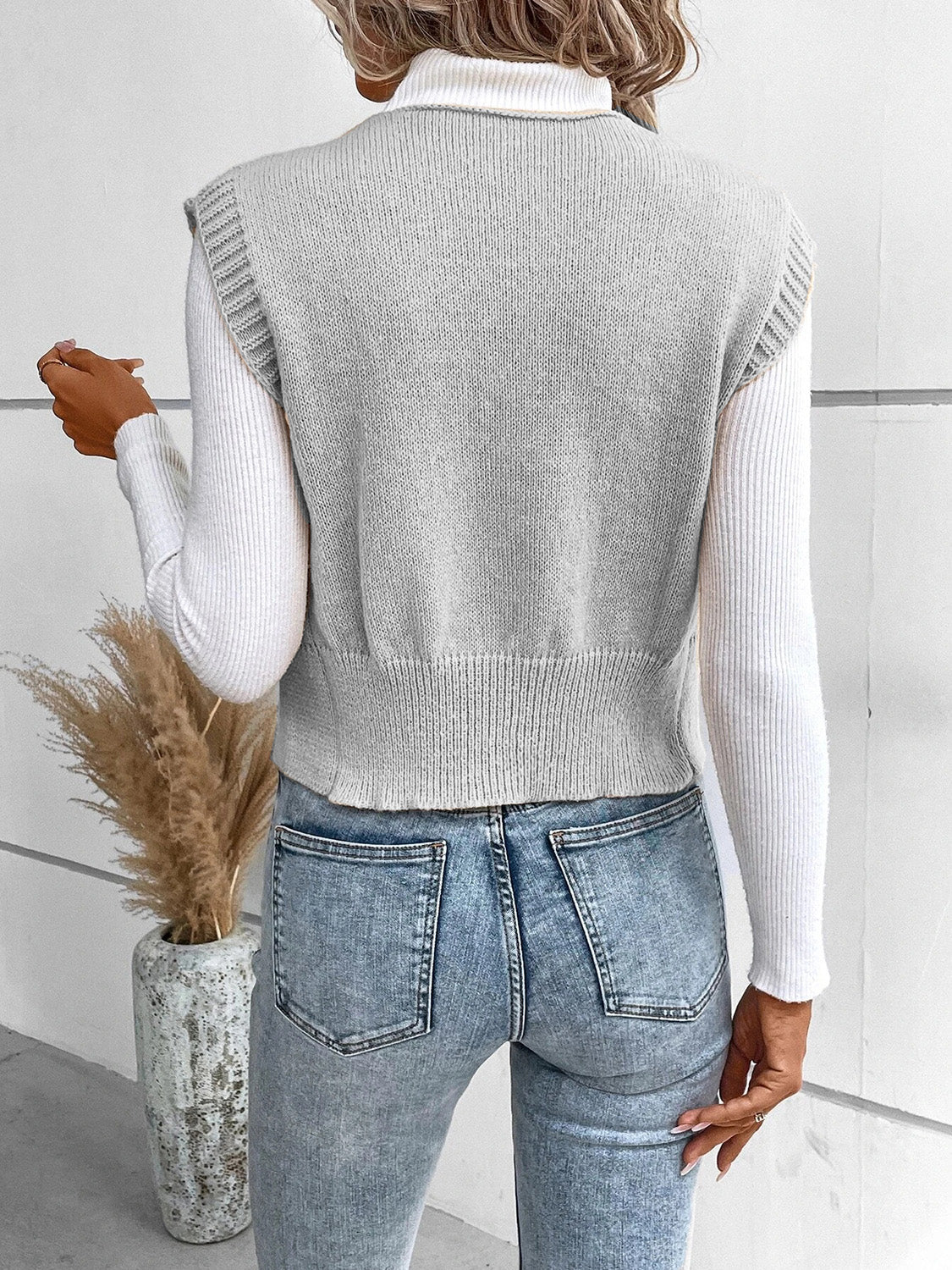 Gray knit vest with ribbed trim and button detail, layered over a white turtleneck.