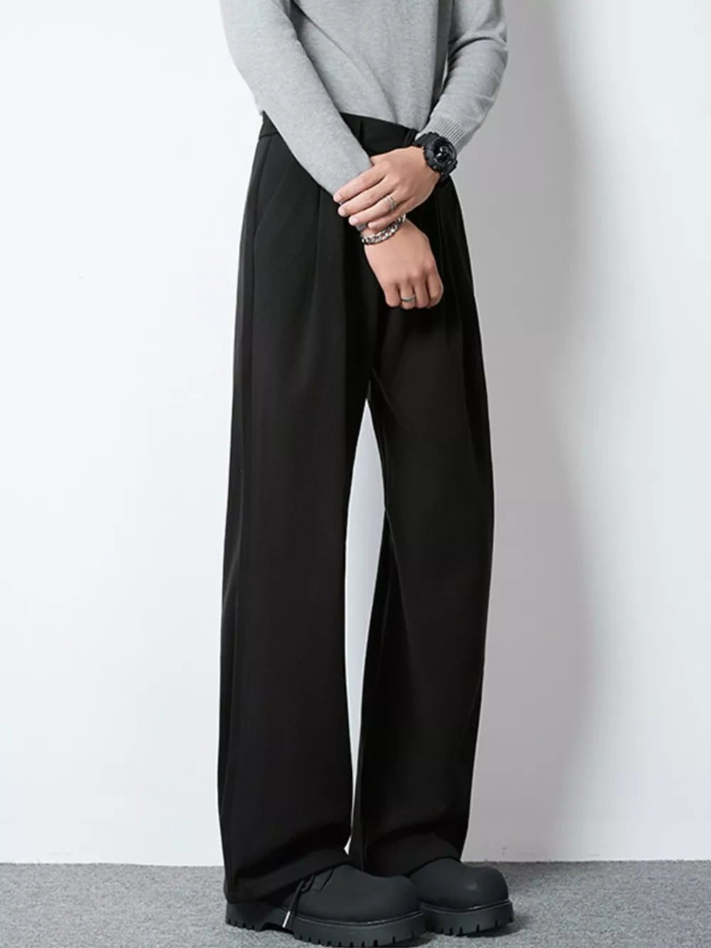 Men's black wide-leg pleated trousers with a relaxed fit.