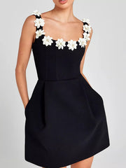 Black mini dress with floral embellishments on straps and neckline, featuring pockets.