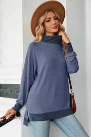 Colorblock raglan turtleneck tunic in dusty blue with dark blue accents, featuring side slits and a relaxed fit.