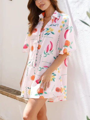 Blush pink romper with fruit and chili print, short sleeves, collared, buttoned front.