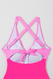 Hot pink one-piece swimsuit with cross-back straps and a bow detail at the back.