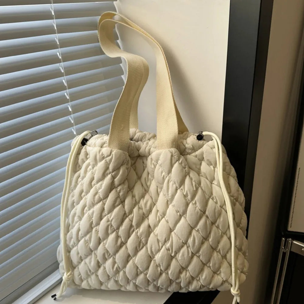 Quilted drawstring carryall handbag in ivory with diamond pattern and canvas straps.
